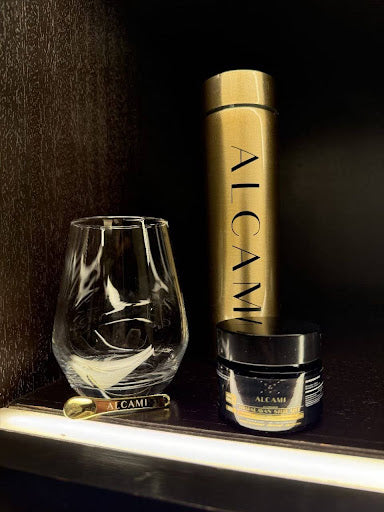 Alcami Elements’ gold thermos, glass tumbler, spoon, and a black jar of Himalayan Shilajit arranged aesthetically.