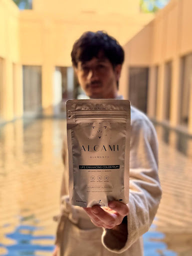 A silver packet of Life Enhancing Colostrum from Alcami Elements held by a man.